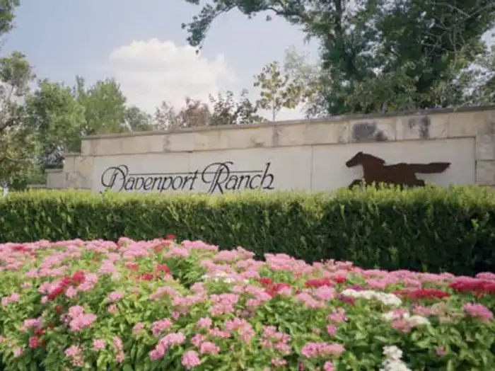 Davenport Ranch entrance wall with a horse silhouette behind pink flower beds, West Lake Hills area, Texas